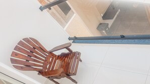A wooden chair with a curved backrest and armrests, positioned on a balcony with a tiled floor. - Residencial Jardins de Taperapuã 2 (Porto Seguro)