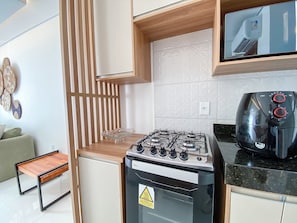A compact kitchen with a gas stove, a coffee maker, and a small table.