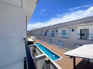 A hotel with a swimming pool, multiple balconies, and a view of the surrounding buildings.