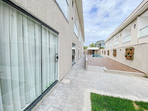 Un edificio residencial con piscina, terraza techada y zona verde.