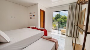 A bedroom with a bed, a red throw, a wooden door, and a balcony with a view of trees. - Residencial Jardins de Taperapuã 2 (Porto Seguro)