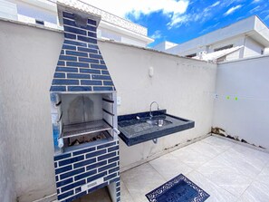 A brick-built outdoor kitchen with a sink and a step stool. - Residencial Jardins de Taperapuã 2 (Porto Seguro)
