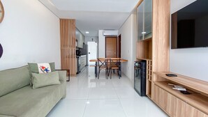 A modern living room with a sofa, TV, and a dining area with chairs and a table.