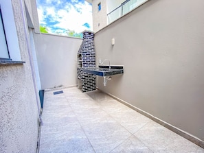 A small outdoor area with a brick-built barbecue, a sink, and a tiled floor. - Residencial Jardins de Taperapuã 2 (Porto Seguro)