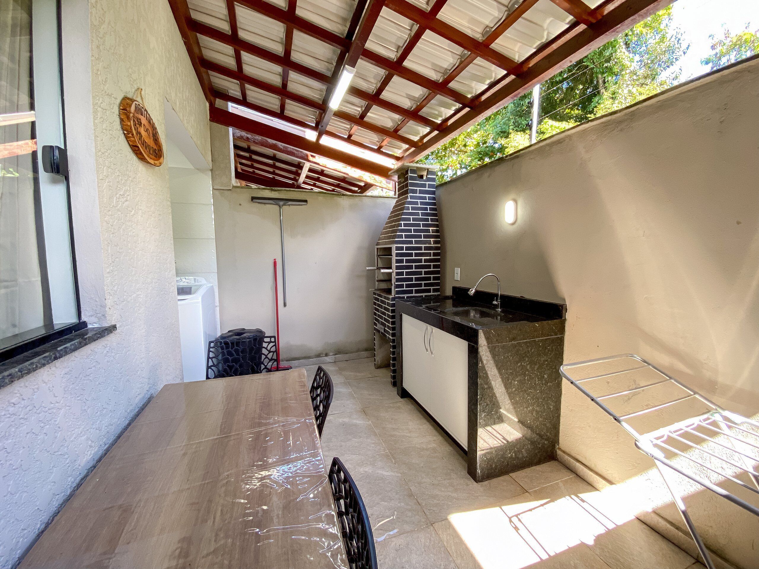 Area cucina esterna con barbecue, lavello e tavolo.