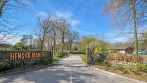 A sign for Hengar Manor Holiday Park with a road leading through a landscaped area. - Cornish Woodland Retreat (Bodmin)