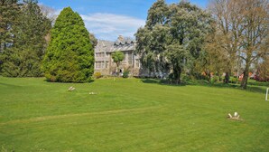 A large, historic building with a well-maintained lawn and mature trees. - Cornish Woodland Retreat (Bodmin)