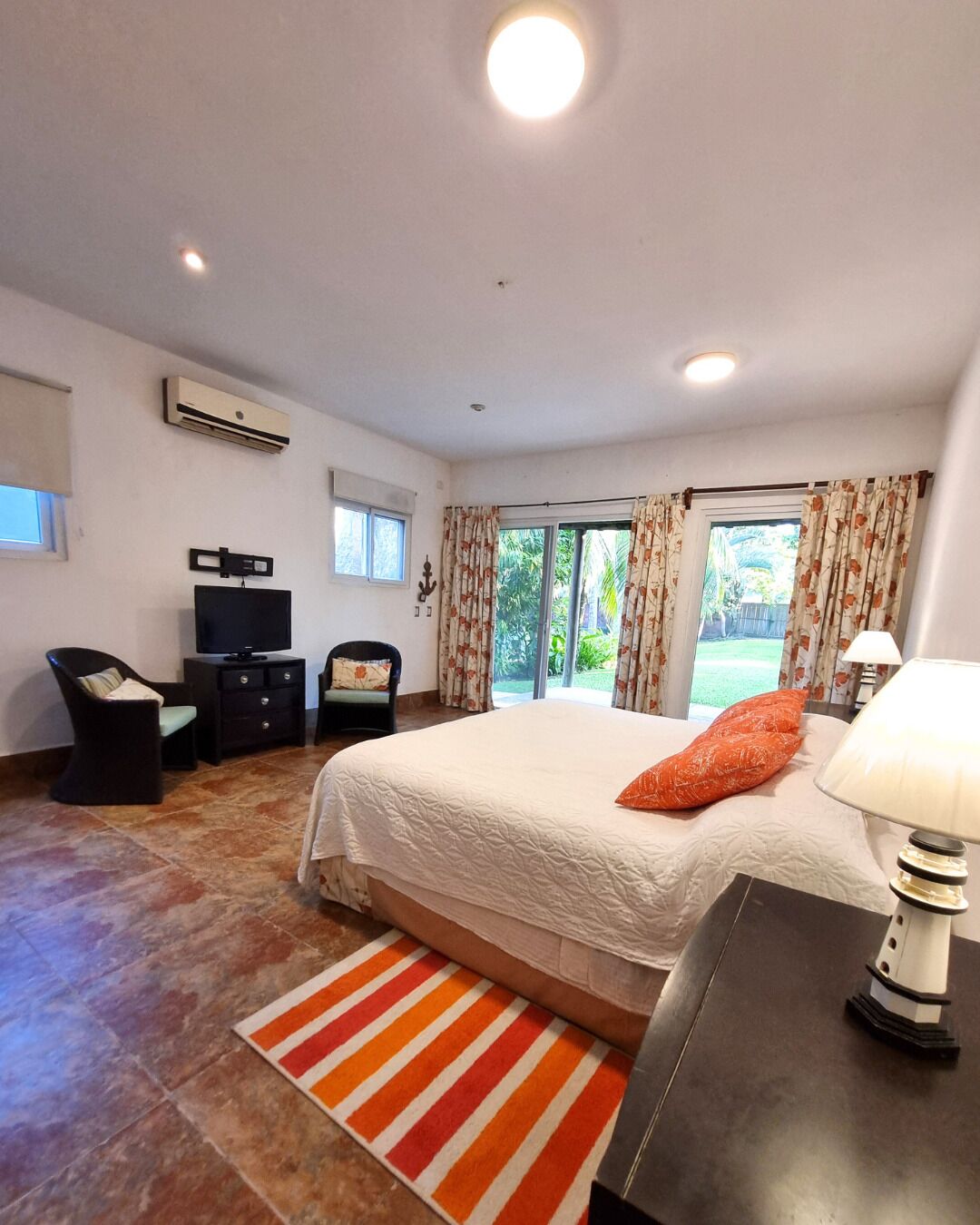 A bedroom with a bed, a desk, a chair, an air conditioner, and a window with curtains.