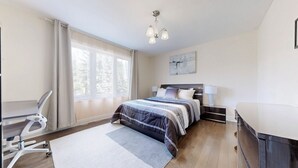 Un dormitorio moderno con una cama grande, mesitas de noche, un escritorio y una silla.