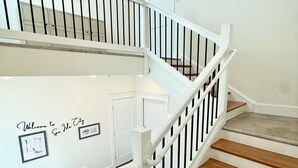 A staircase with white railings and wooden steps, leading to an upper floor. - Beach Block Downtown Luxury Walk to Everything! (Sea Isle City)