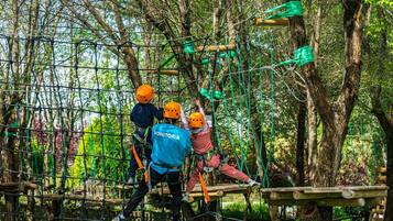 Un circuito de aventura al aire libre con cuerdas y plataformas de madera, rodeado de árboles.