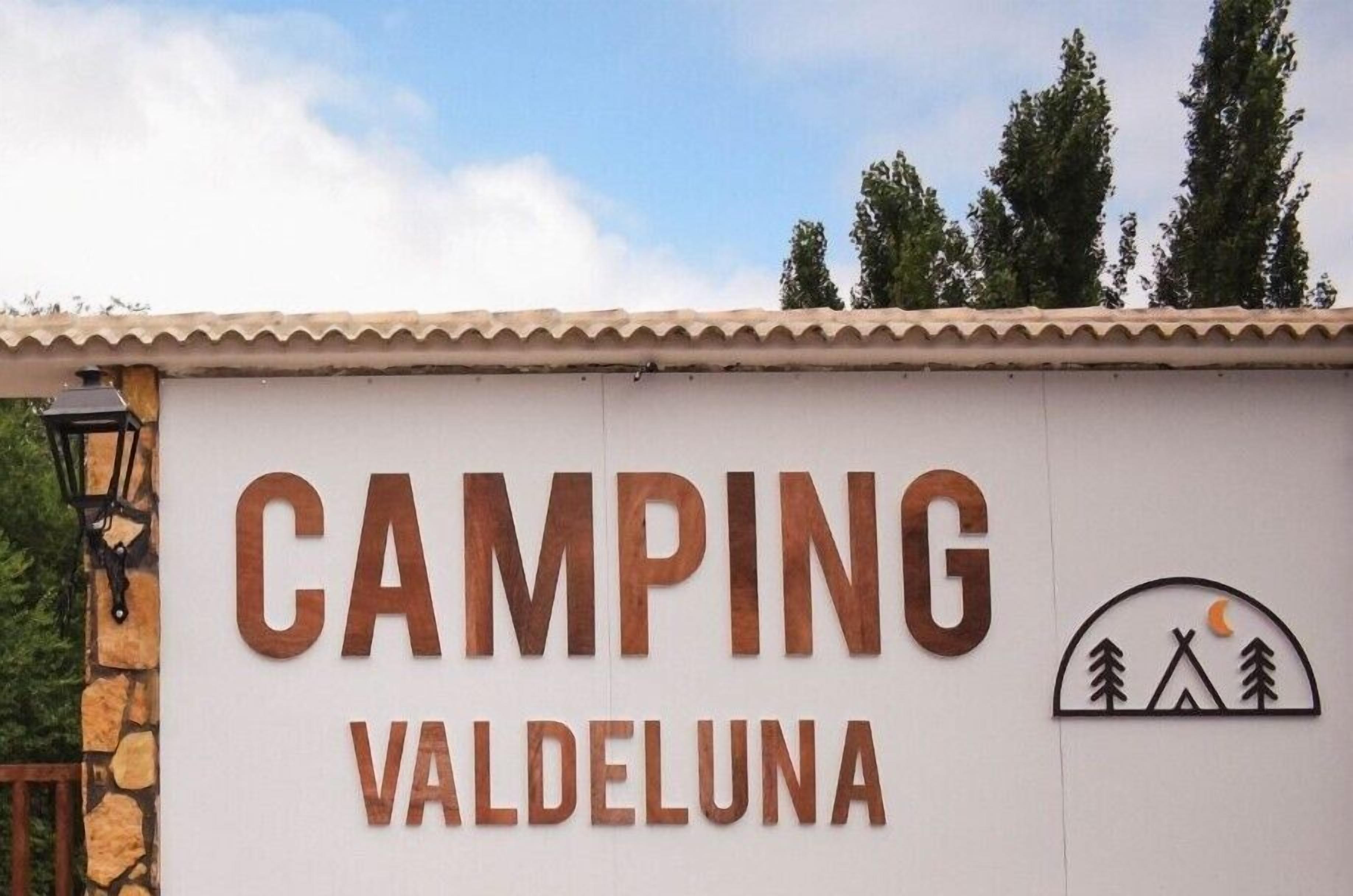 Señal de CAMPING VALDELUNA, con un símbolo de camping y árboles.