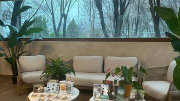 A modern living room with a sofa, two coffee tables, and potted plants.