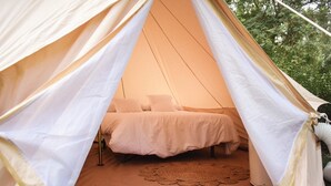 A tent with a bed inside, a woven mat on the floor, and a window.