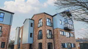 A multi-story residential building with brick and siding exteriors, balconies, and a paved driveway. - Brewery View (Weymouth)