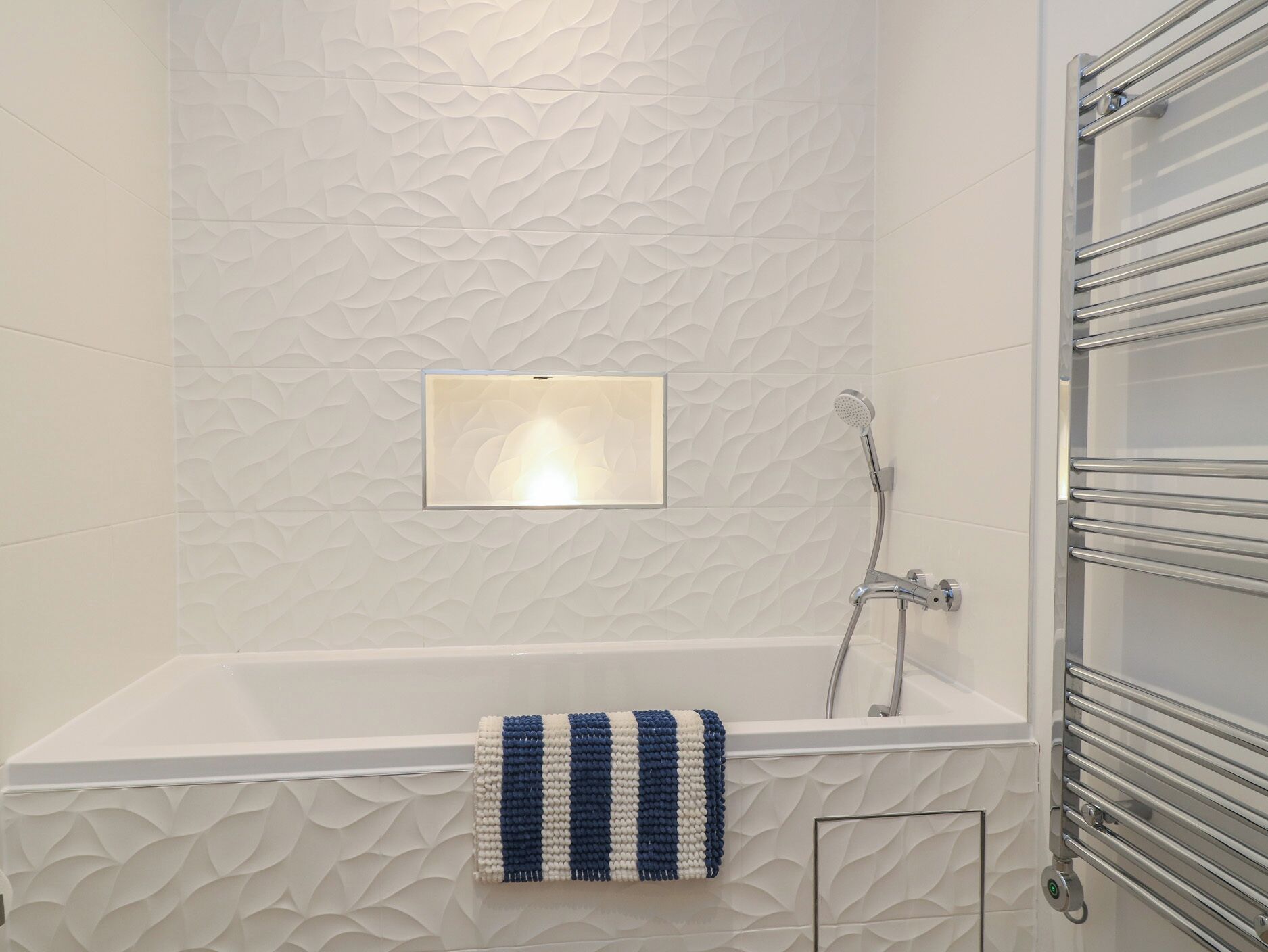 Une salle de bain moderne avec un mur à texture, une douche intégrée et un porte-serviettes.