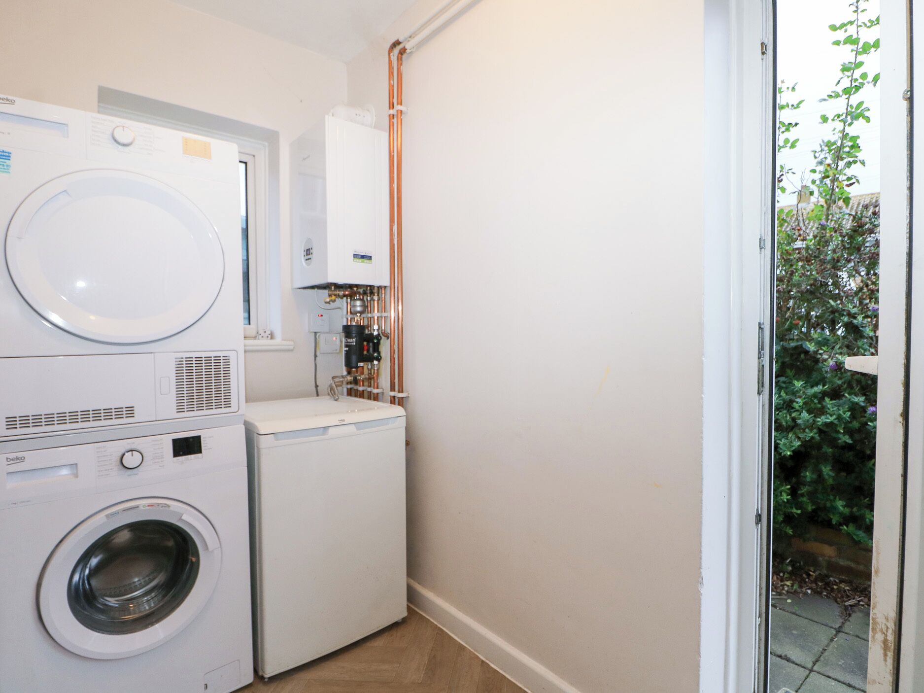 A laundry room with stacked washing machines and a water heater.