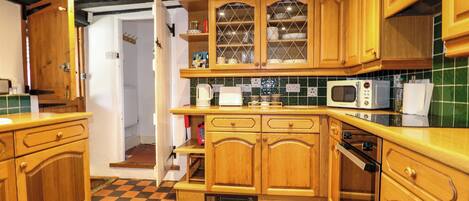 Une cuisine avec des meubles en bois, un four à micro-ondes et un carrelage à carreaux.