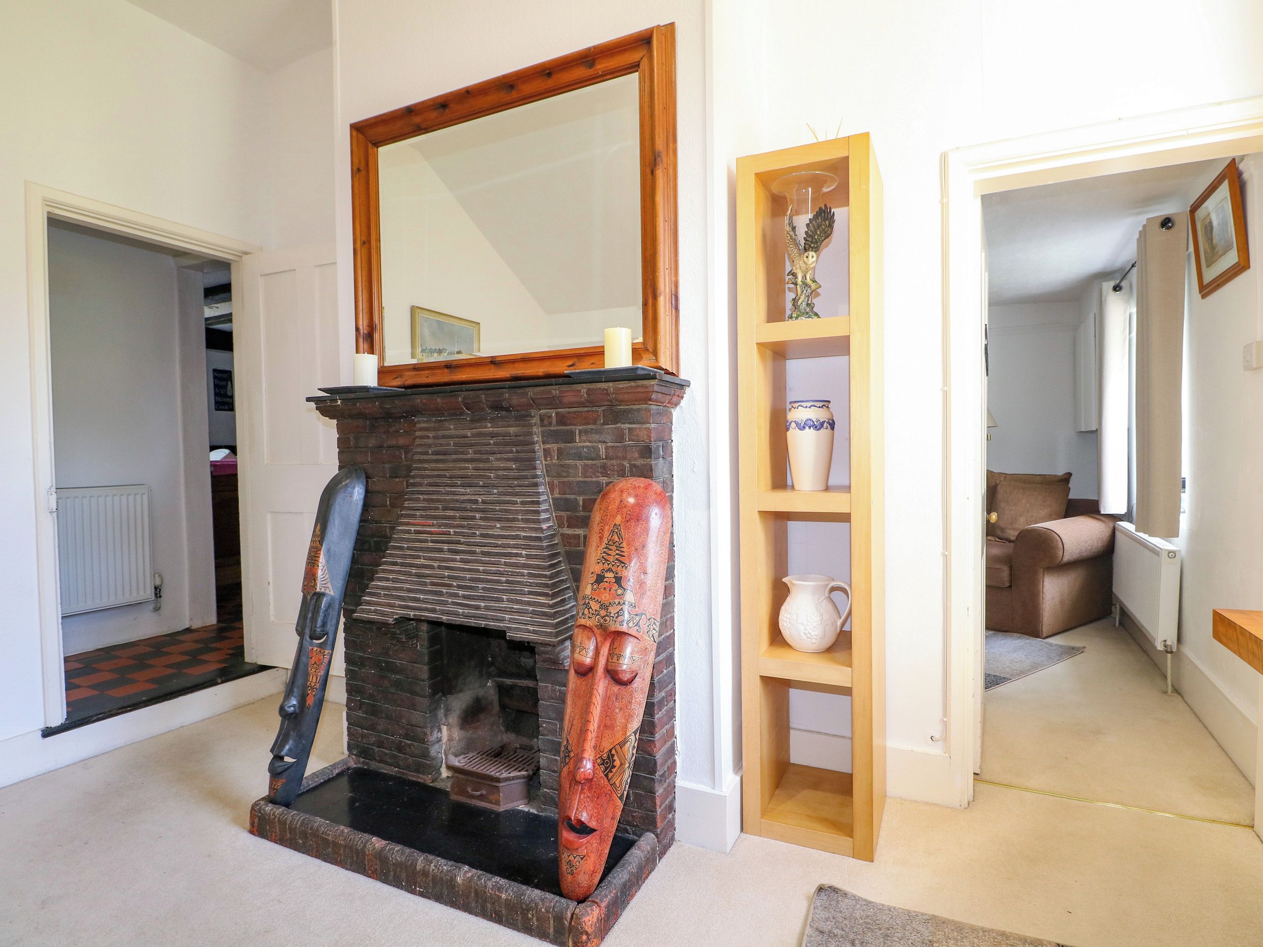 Una habitación con chimenea, un espejo y una estantería con adornos.