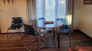 A dining area with a round table, four chairs, and a window with curtains.