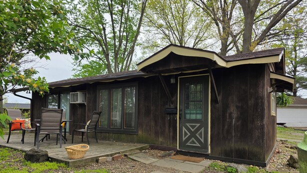 A small wooden cabin with a porch, outdoor seating, and a door with a geometric design.