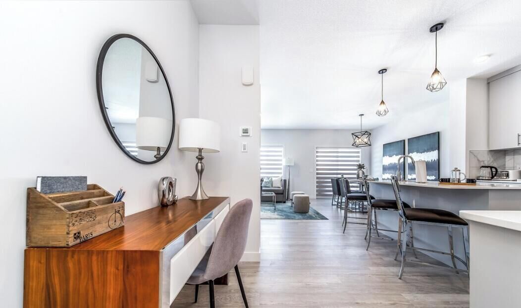 A modern kitchen with a wooden countertop, a round mirror, and pendant lights.