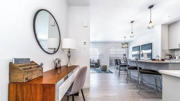 A modern kitchen with a wooden countertop, a round mirror, and pendant lights.