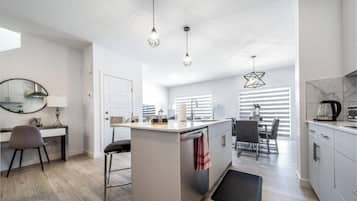 A modern kitchen with a central island, a dining area, and a workspace.