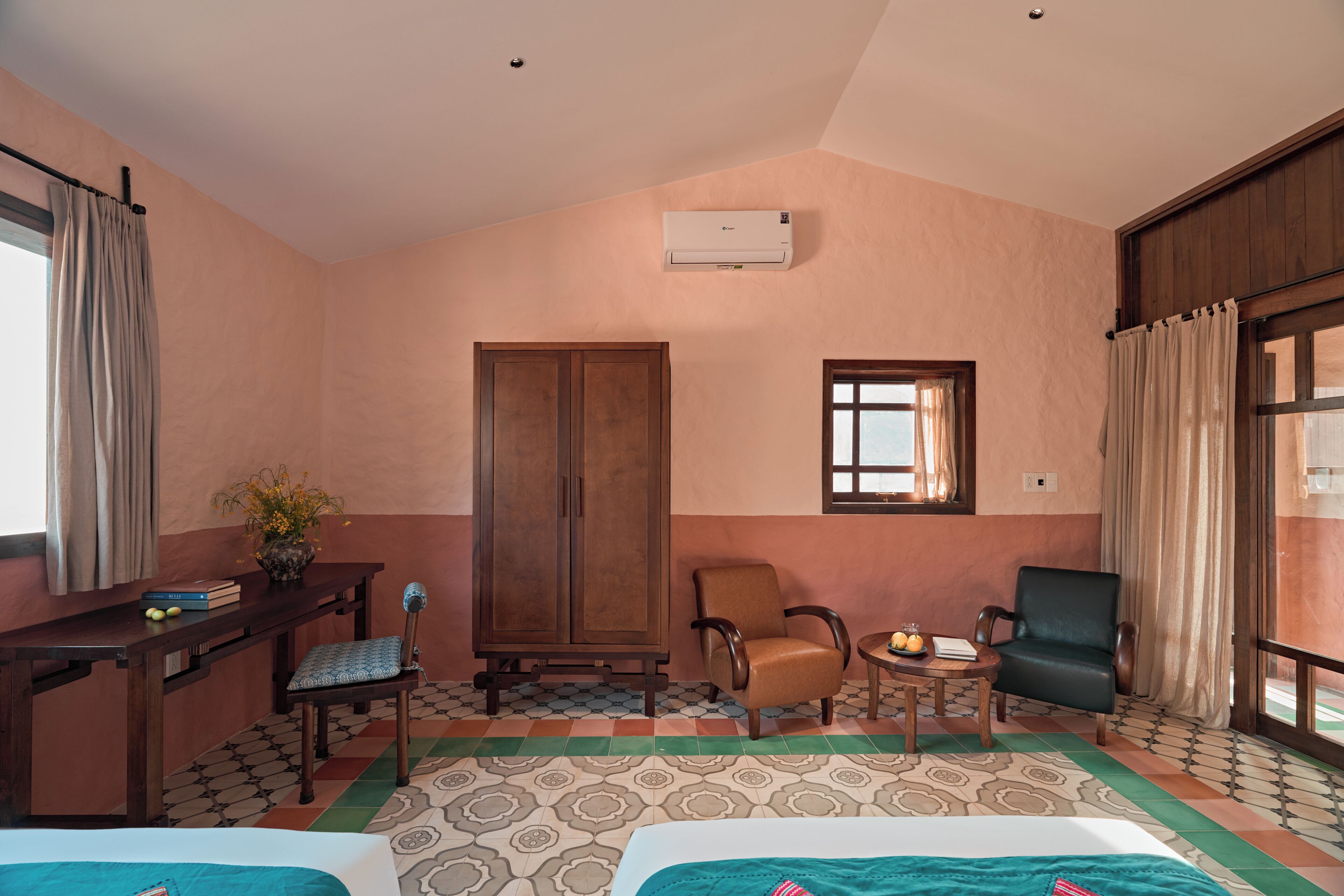 A hotel room with a bed, two chairs, a desk, a wardrobe, and a window.