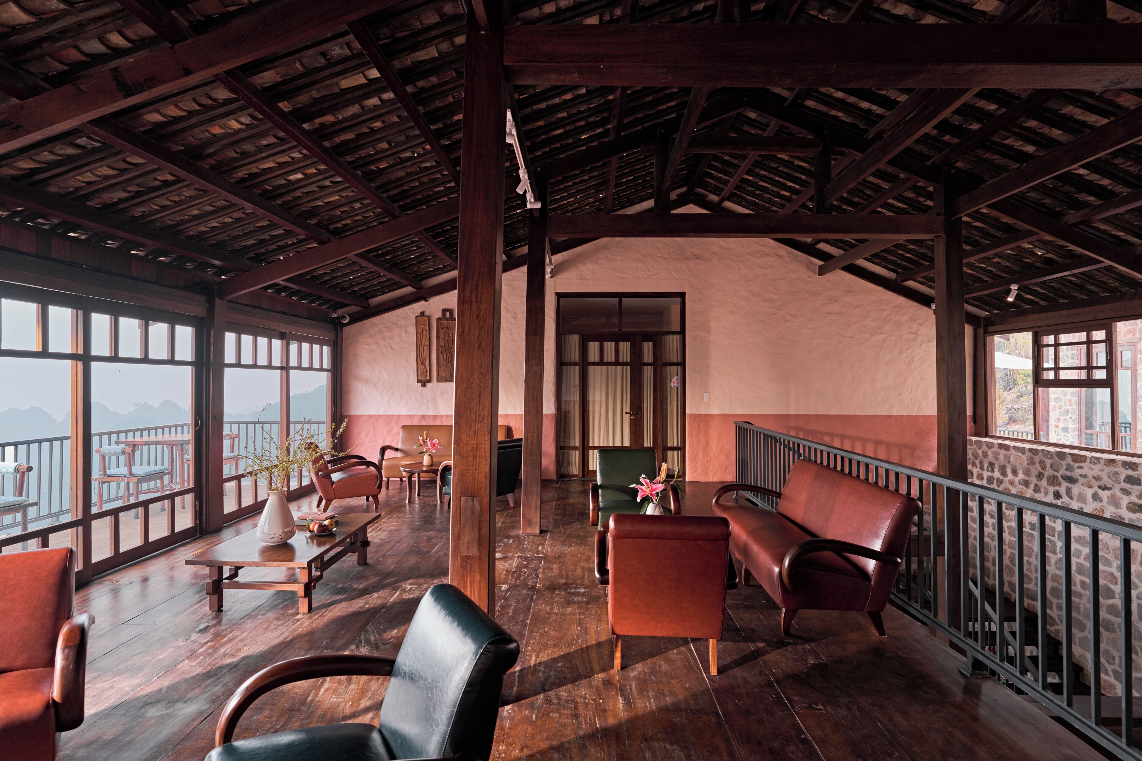 A spacious lounge with wooden flooring, leather seating, and large windows offering mountain views.