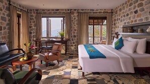 A hotel room with a large bed, a desk, two chairs, and a view of mountains through the window. - Ha Giang Aya Lodge (Lung Phin)