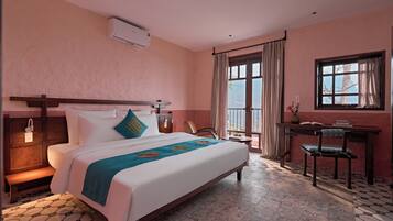 A hotel room with a bed, a desk, a chair, a window, and a balcony.