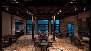 A spacious indoor area with stone walls, large windows, and a variety of seating arrangements. - Ha Giang Aya Lodge (Lung Phin)