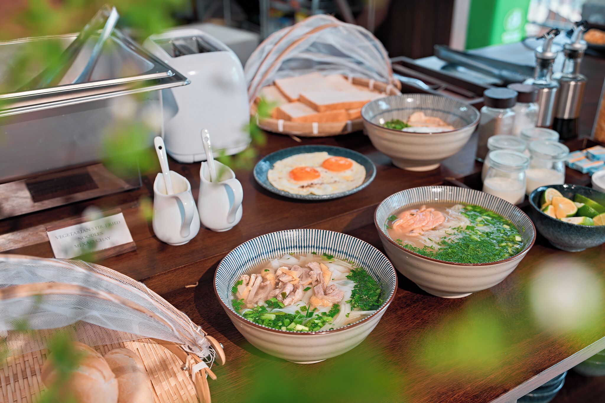 A table with various dishes including bowls of soup, plates of food, and a basket of bread.