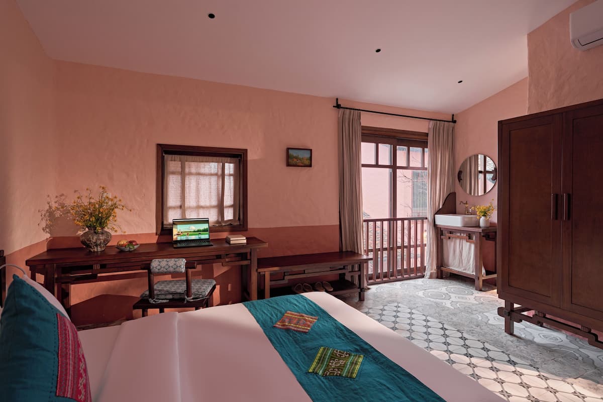 A bedroom with a bed, desk, chair, wardrobe, and a window with curtains.