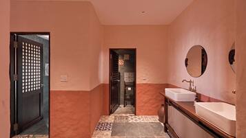 A bathroom with a tiled floor, a sink, a mirror, and a door with a decorative screen.
