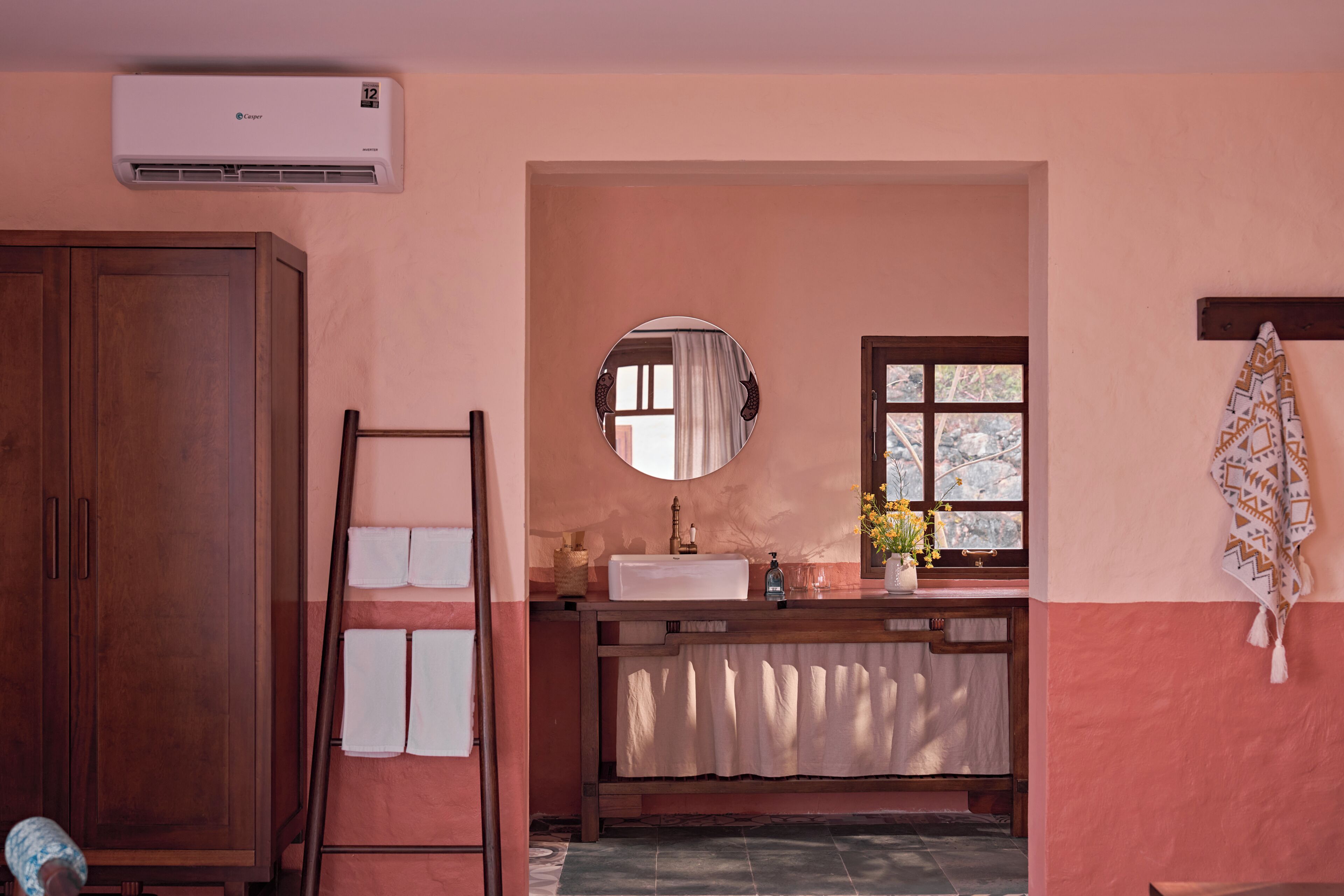 Une salle de bain avec un meuble en bois, un porte-serviettes, un lavabo avec un miroir et une fenêtre donnant sur un paysage agréable.