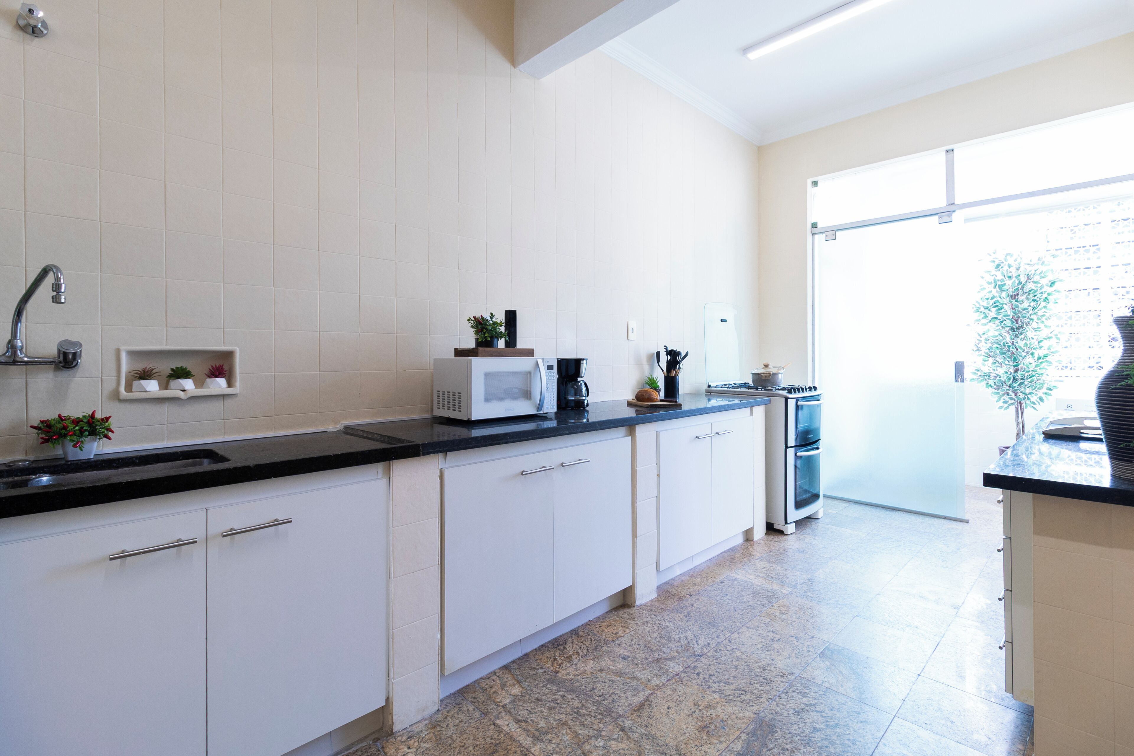 A modern kitchen with white cabinets, a black countertop, and a microwave.