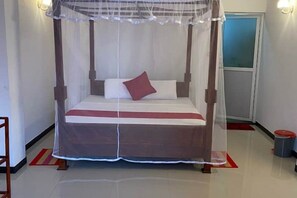 Una cama con dosel, un almohadón rojo y una alfombra a rayas rojas y blancas.