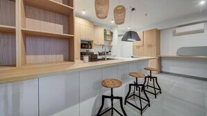 A modern kitchen with wooden shelves, a central island with stools, pendant lighting, and built-in appliances.