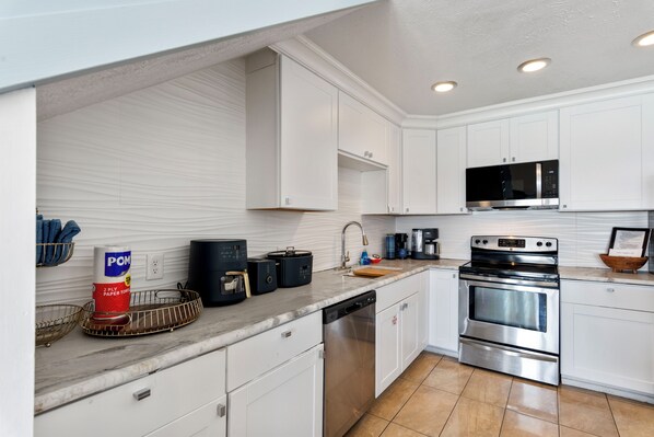 A modern kitchen with white cabinets, stainless steel appliances, and a marble countertop. - 2 story condo with Epic Gulf Views in Crystal Villas B13 (Destin)