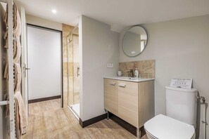 Une salle de bain comprenant une douche, des toilettes, un lavabo avec un miroir et un porte-serviettes.
