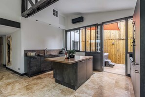A modern kitchen with a large island, dark cabinetry, and a view of a wooden fence through the window. - Charming workshop with jacuzzi near St-Emilion (Branne)