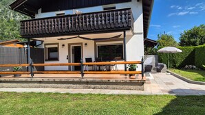 Un bâtiment à deux étages doté d’un balcon, d’un espace extérieur aménagé pour s’asseoir et d’un jardin bien entretenu.