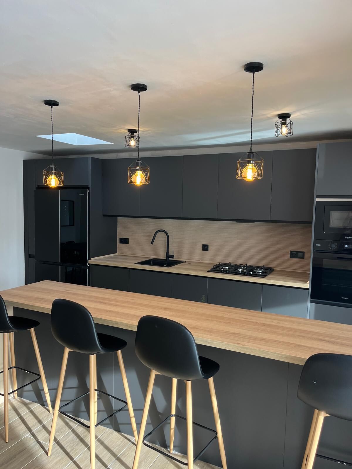 A modern kitchen with a central island, bar stools, and pendant lighting.