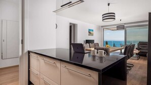 Una cocina moderna con encimera negra, electrodomésticos integrados y vistas al océano.