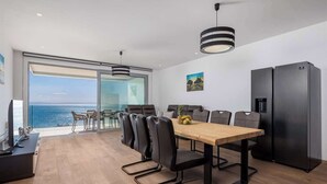 Un comedor moderno con una mesa de madera, sillas negras y un refrigerador negro.