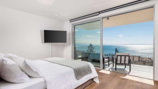 Un dormitorio con cama, televisión y balc ón con vistas al mar.