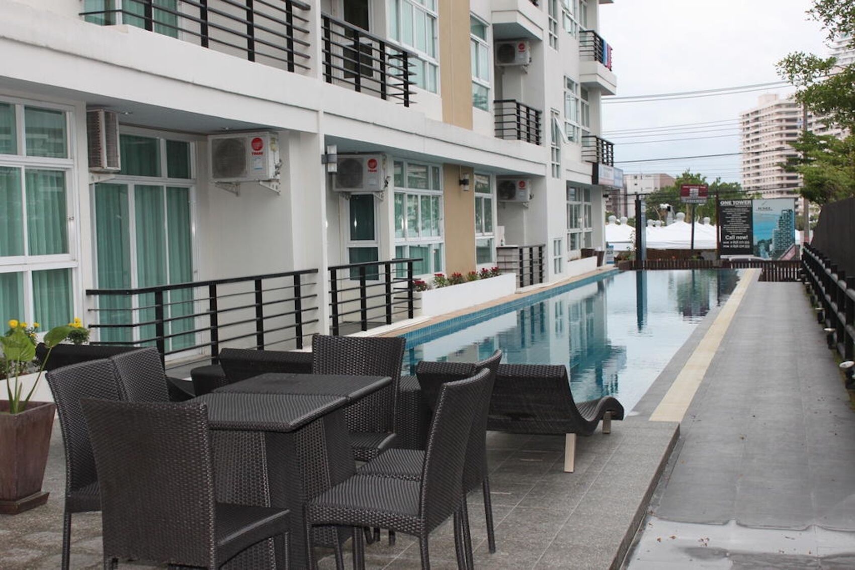 A hotel with a swimming pool, outdoor seating, and a view of the city.