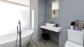 Une salle de bain moderne avec une baignoire sur pieds, un lavabo blanc et des toilettes.
